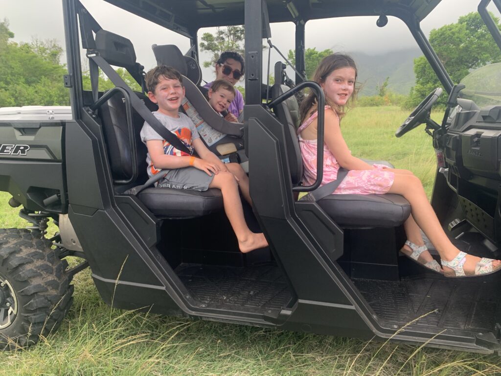 A mother and three smiling children in a golf cart.