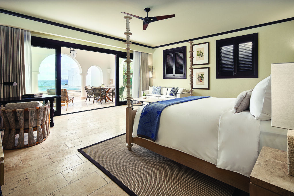 An ocean view bedroom at Cap Juluca with a king bed wiht white and blue bedding and large terrace. 