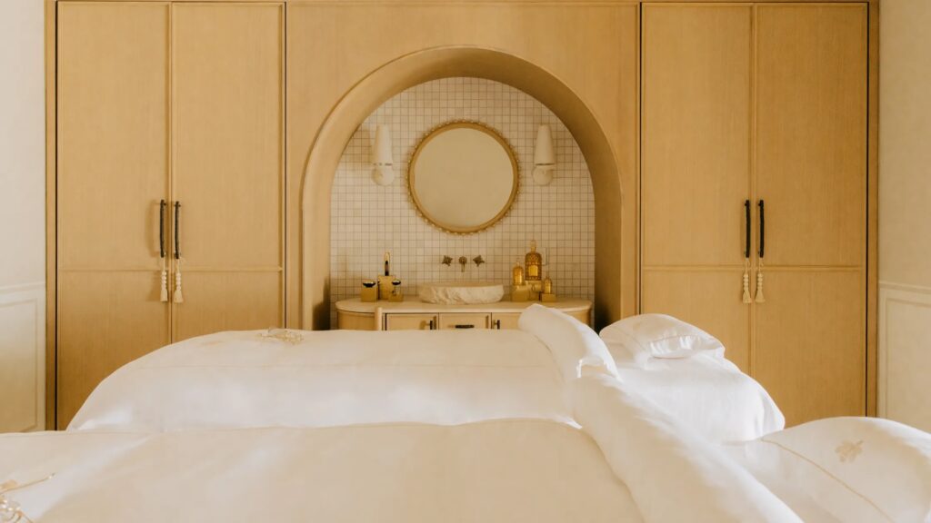 View of two massage tables in front of built in cabinetry that is light wood colored.