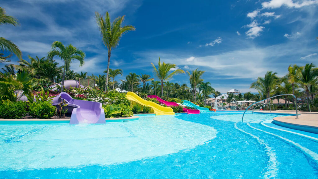 A sparkling blue childrens pool with purple, yellow, pink and aqua slides for children.